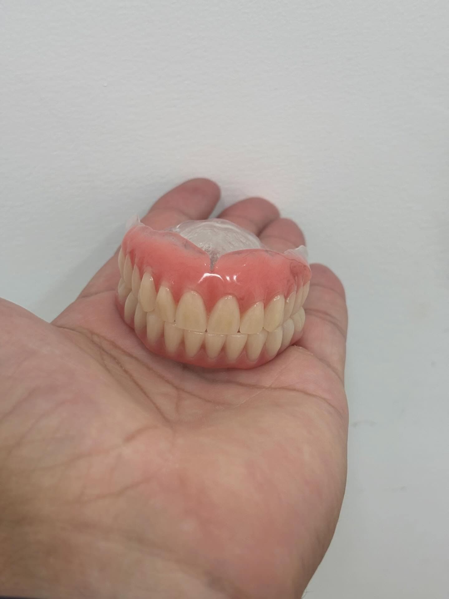 Prótese dentária na palma da mão, boa iluminação e foco.